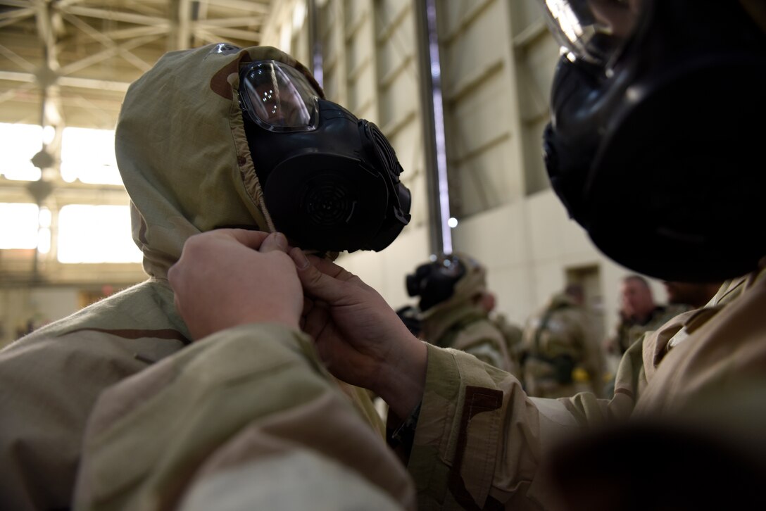 U.S. Air Force Airman First Class Jared Chapman, 145th Civil Engineering Squadron, assists his wingman with securing their mission oriented protective posture suit during an Ability To Survive and Operate (ATSO) training held in a C-17 Globemaster III hangar at the North Carolina Air National Guard (NCANG) Base, Charlotte Douglas International Airport, Jan. 10, 2019. The ATSO exercise consists of ten rotating stations and serves as refresher training for situations like self-aid buddy care, explosive ordinance device recognition, and chemical warfare decontamination stations.