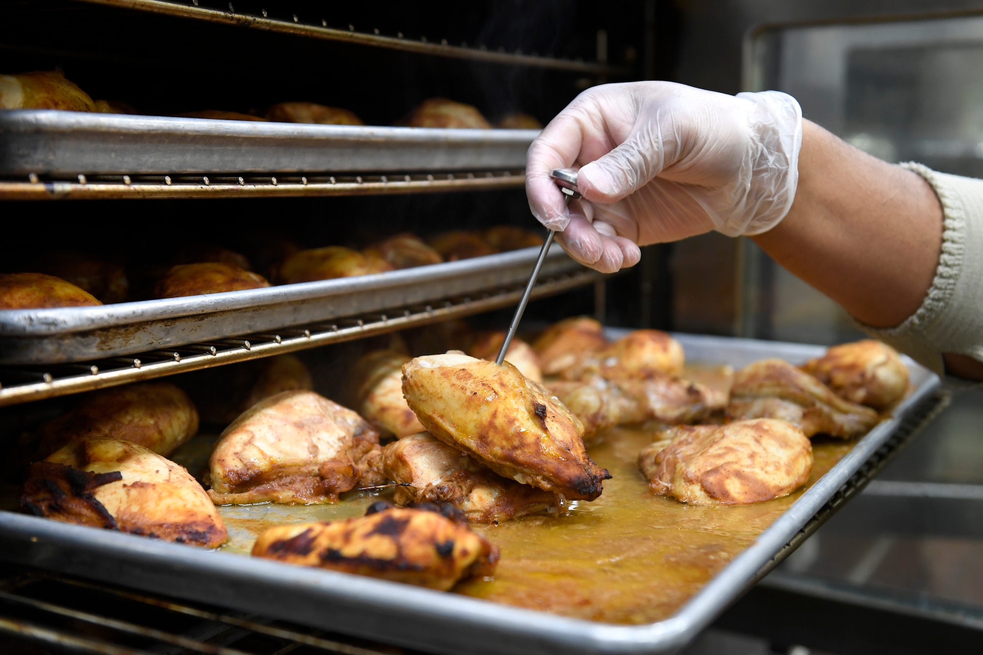 A member from the 145th Force Support Squadron checks the temperature of the chicken to be served for lunch at the North Carolina Air National Guard Base, Charlotte Douglas International Airport, Jan. 12, 2019. Food services Airmen from the North Carolina Air National Guard train members from the Niagara Falls Air Reserve Station, New York, on full-service kitchen operations in preparation for the upcoming Air Force active duty and reserve Hennessy Award competition.