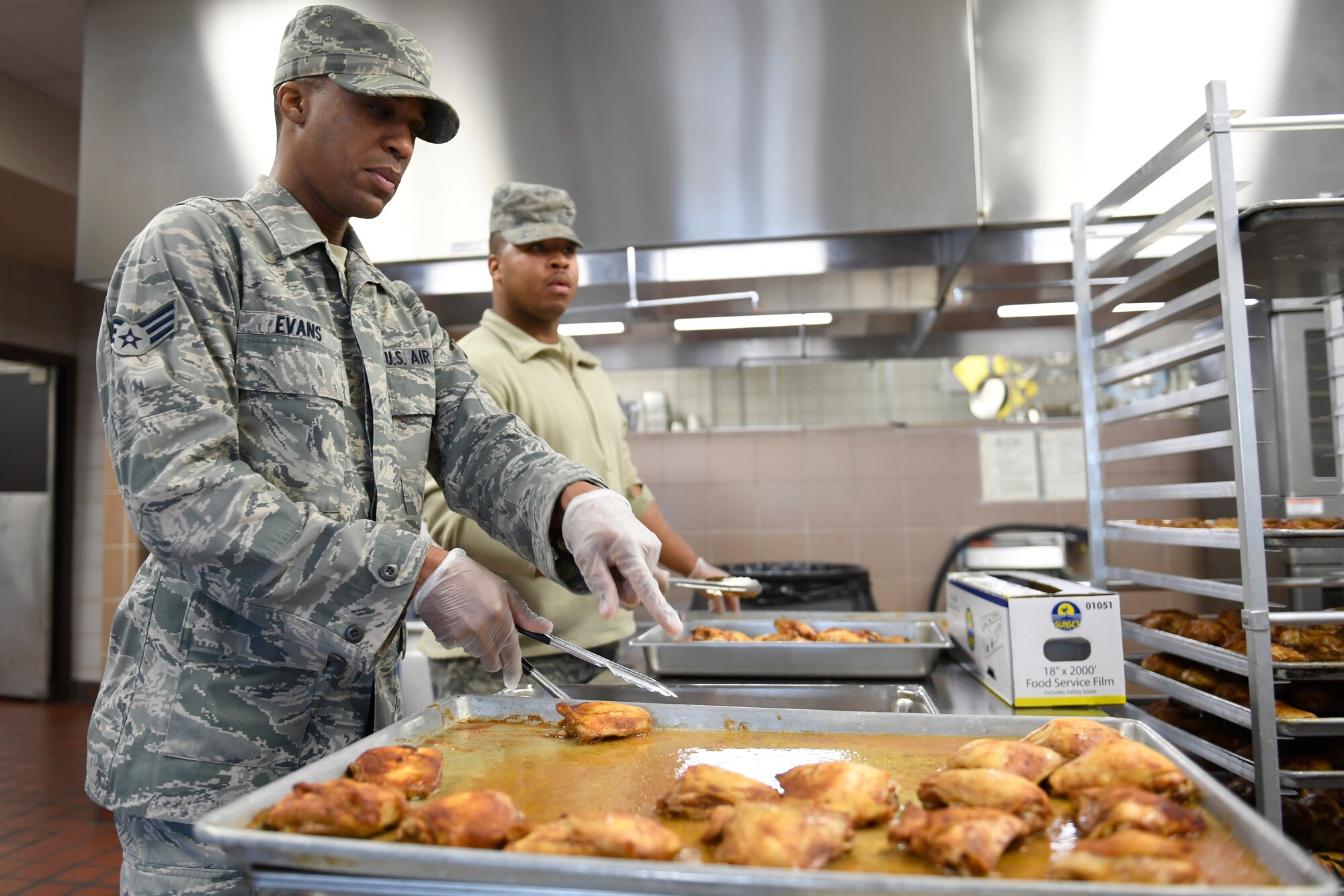 U.S. Air Force Senior Airman Derek Evans (left) Senior Airman Deontre Barrett (right), 145th Force Support Squadron, prepare cooked chicken to be served for lunch in the dining facility during drill weekend at the North Carolina Air National Guard Base, Charlotte Douglas International Airport, Jan. 12, 2019. Food services Airmen from the North Carolina Air National Guard train members from the Niagara Falls Air Reserve Station, New York, on full-service kitchen operations in preparation for the upcoming Air Force active duty and reserve Hennessy Award competition.