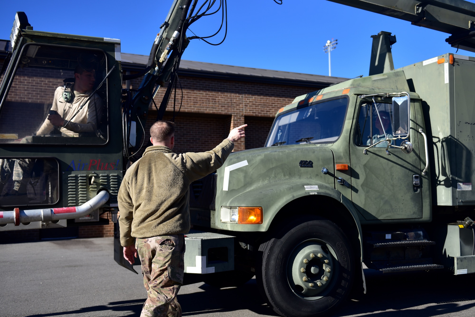 A man points at Airmen in a de-icing truck.