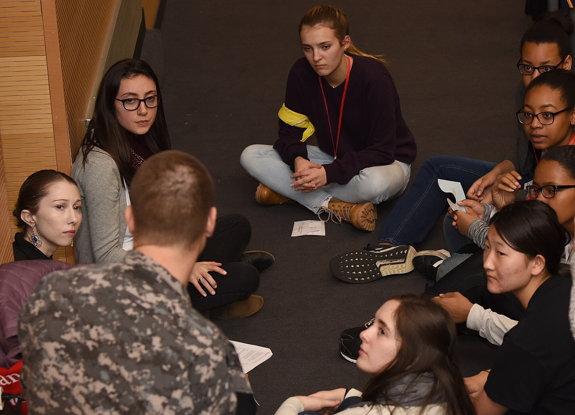 A U.S. Air Force Survival, Evasion, Resistance and Escape specialist from the 352nd Special Operations Support Squadron talks to Lakenheath High School students during the Raid Cross program at Royal Air Force Lakenheath, England, Jan. 11, 2019. The SERE specialists assisted the American Red Cross-hosted event by demonstrating prisoner of war scenarios. (U.S. Air Force photo by Airman 1st Class Madeline Herzog)