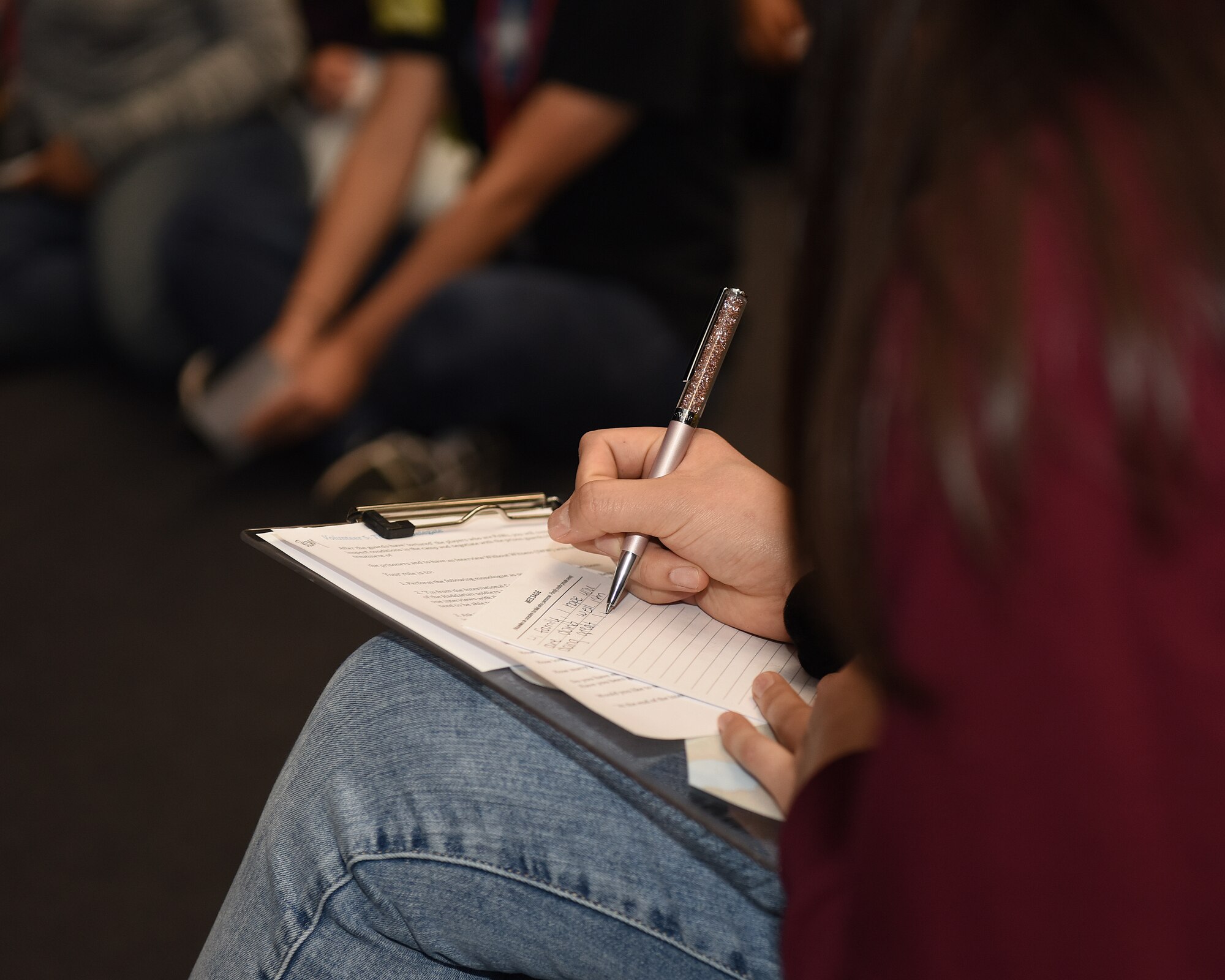 Kylie Okura, Lakenheath High School Red Cross Club president and child of an active duty Airman, simulates writing a letter home during a prisoner of war scenario at the school auditorium at Royal Air Force Lakenheath, England, Jan. 11, 2019. The American Red Cross hosted the International Humanitarian Law Youth Action Campaign and Raid Cross event, Jan. 11-12. (U.S. Air Force photo by Airman 1st Class Madeline Herzog)