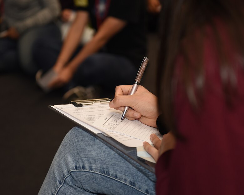 Kylie Okura, Lakenheath High School Red Cross Club president and child of an active duty Airman, simulates writing a letter home during a prisoner of war scenario at the school auditorium at Royal Air Force Lakenheath, England, Jan. 11, 2019. The American Red Cross hosted the International Humanitarian Law Youth Action Campaign and Raid Cross event, Jan. 11-12. (U.S. Air Force photo by Airman 1st Class Madeline Herzog)