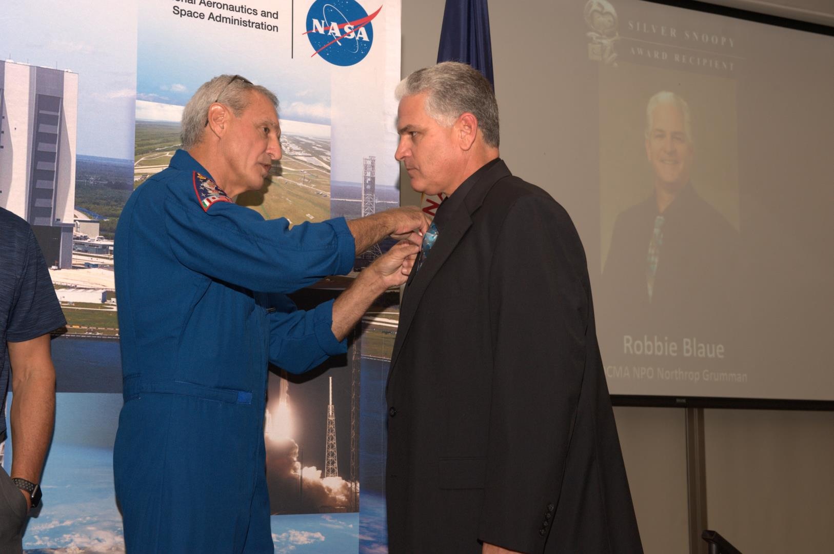 A man pins an award on another man