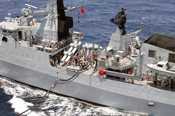 Safety observers from Military Sealift Command’s dry cargo and ammunition ship USNS Washington Chambers stand alongside Royal Malaysian Navy sailors aboard frigate RMN KD Lekiu during an underway replenishment.