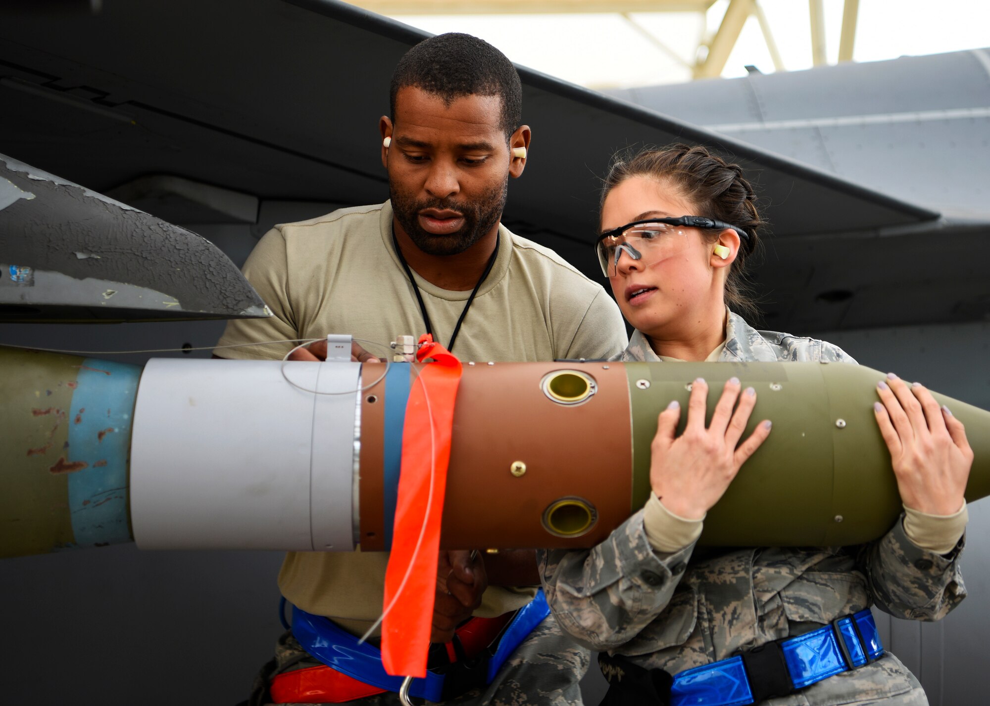 Staff Sgt. Albert Banks and Senior Airman Nadiya Frick, 309th Aircraft Maintenance Unit load crew team members, load an inert bomb onto an F-16 Fighting Falcon at Luke Air Force Base, Ariz., Jan. 10, 2019.