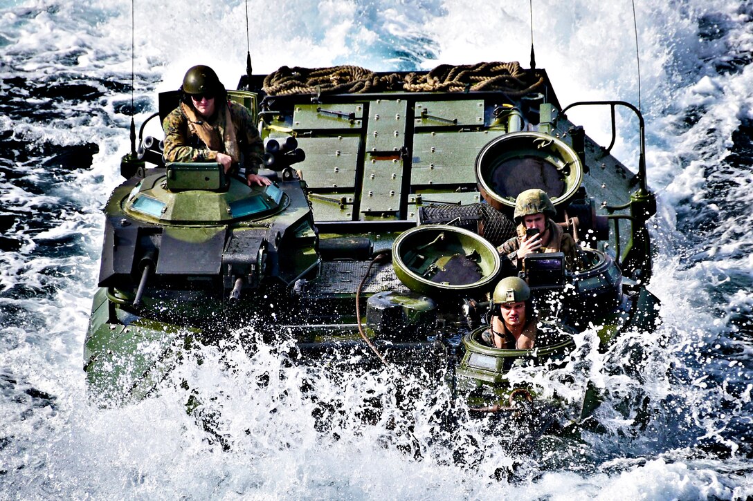 Three Marines sit inside a water vehicle in the sea.