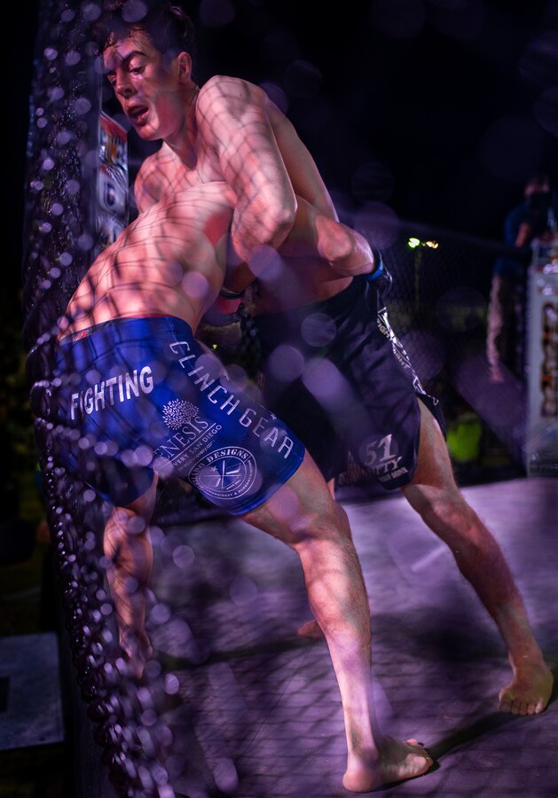 A fighter pushes his opponent against the cage at Del Valle Field, Marine Air Ground Combat Center, Twentynine Palms, Calif. on October 12, 2018. Fight Night is an annual event hosted by Marine Corps Community Services to boost the morale of service members aboard the Combat Center. (U.S. Marine Corps photo by Lance Cpl. Carley Vedro)