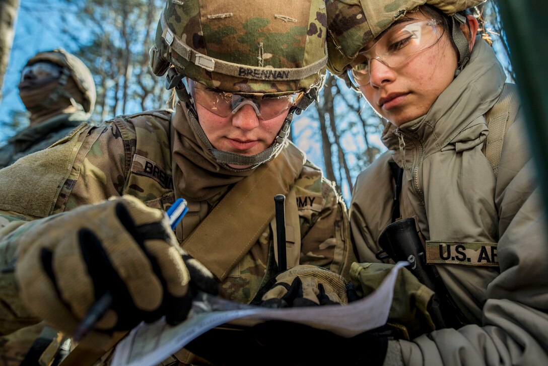 Two soldiers look at a map.