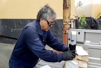 Defense Logistics Agency Energy Hawaii Quality Assurance Representative Daniel Muranaka handles a sample from one of Naval Facilities Engineering Command Hawaii fuel oil reclaimed tanks. The samples were delivered to Island Energy Services to conduct testing.