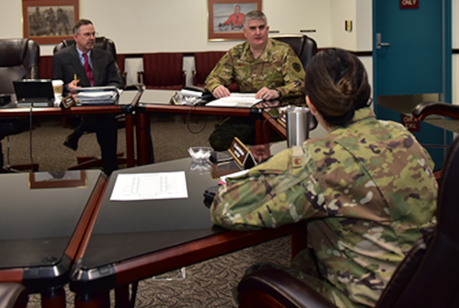Three individuals hold meeting at a table, two military and one civilian