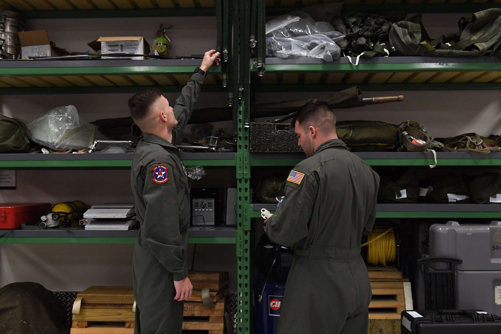 Two men stand in front of shelves.