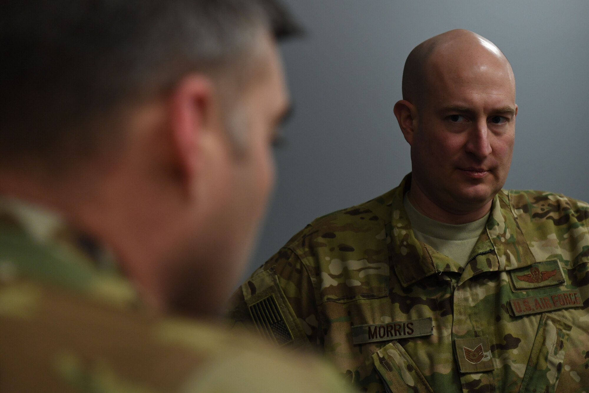 A man looks at a man in the foreground of the photo.