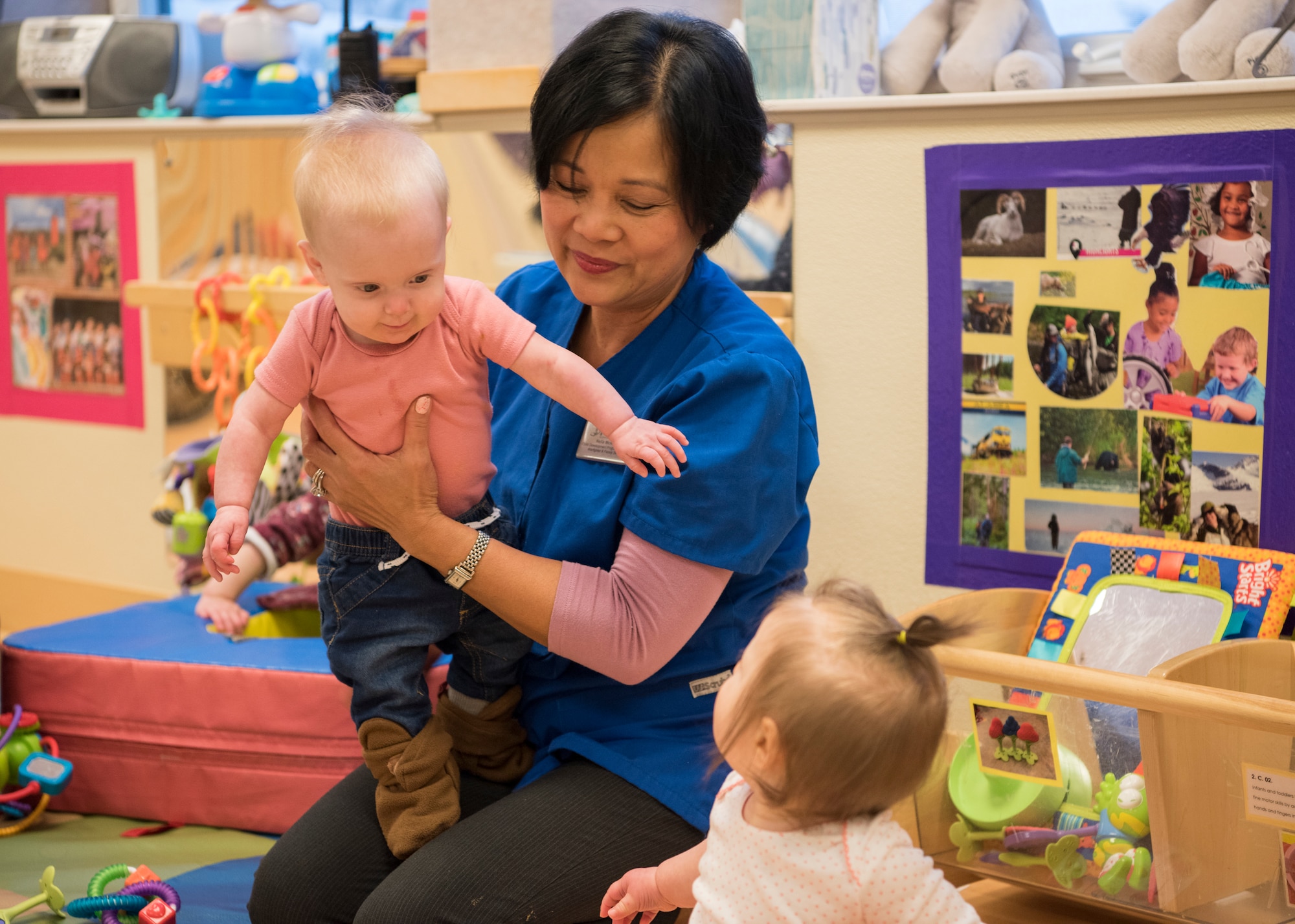Nelia McKeown, a Sitka Child Development Center child and youth program assistant, holds a child during playtime at Joint Base Elmendorf-Richardson, Alaska, Dec. 14, 2018. All five JBER CDC centers are accredited by the National Association for the Education of Young Children and provide childcare for ages 6 weeks to 5 years. Due to a shortage in workers JBER is hiring child development center workers – including teachers, cooks and food service workers.