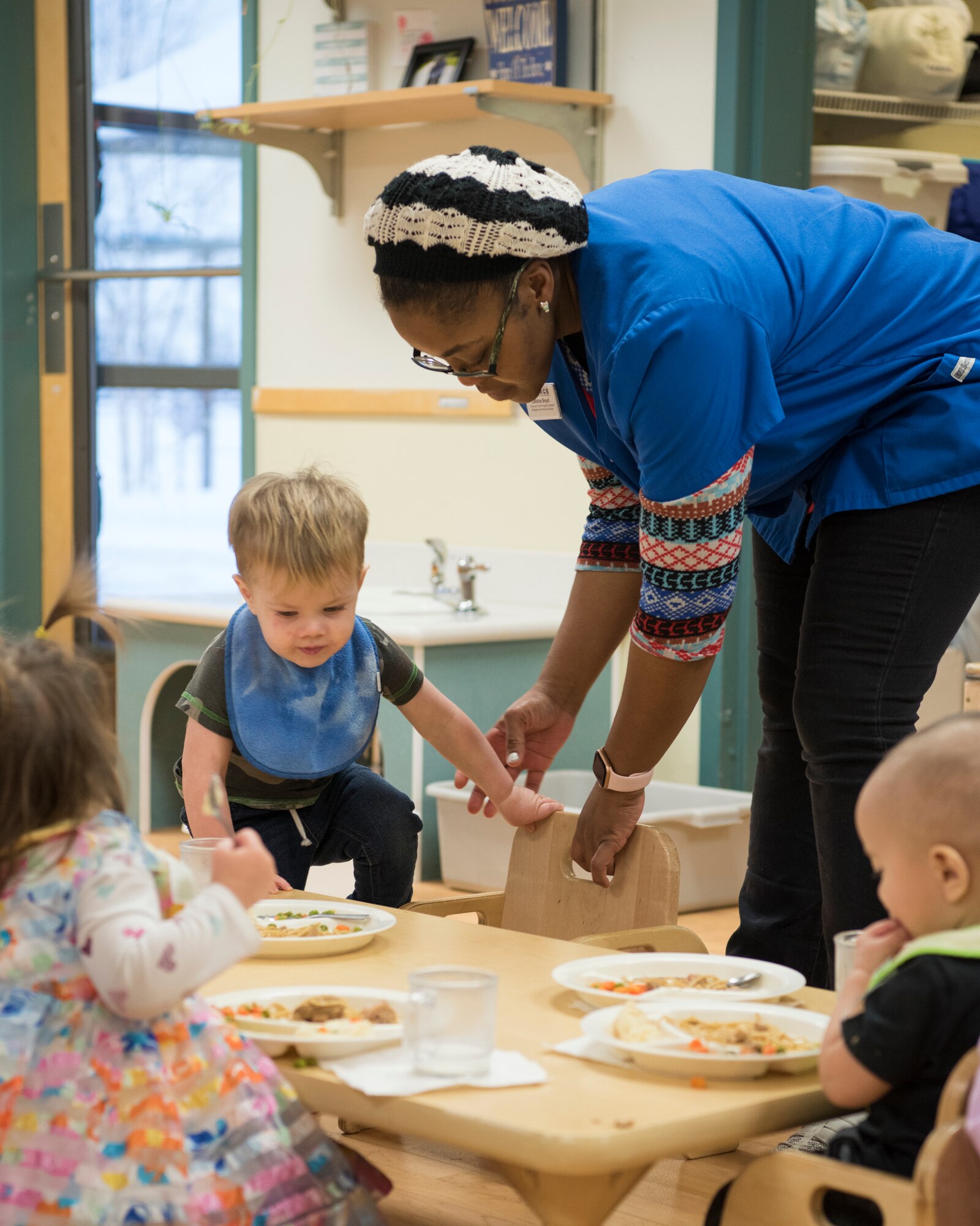 Latisha Boyd, a Sitka Child Development Center child and youth program assistant, teaches children to sit and eat at a table during meal time at Joint Base Elmendorf-Richardson, Alaska, Dec. 14, 2018. All five JBER CDC centers are accredited by the National Association for the Education of Young Children and provide childcare for ages 6 weeks to 5 years. Due to a shortage in workers JBER is hiring child development center workers – including teachers, cooks and food service workers.