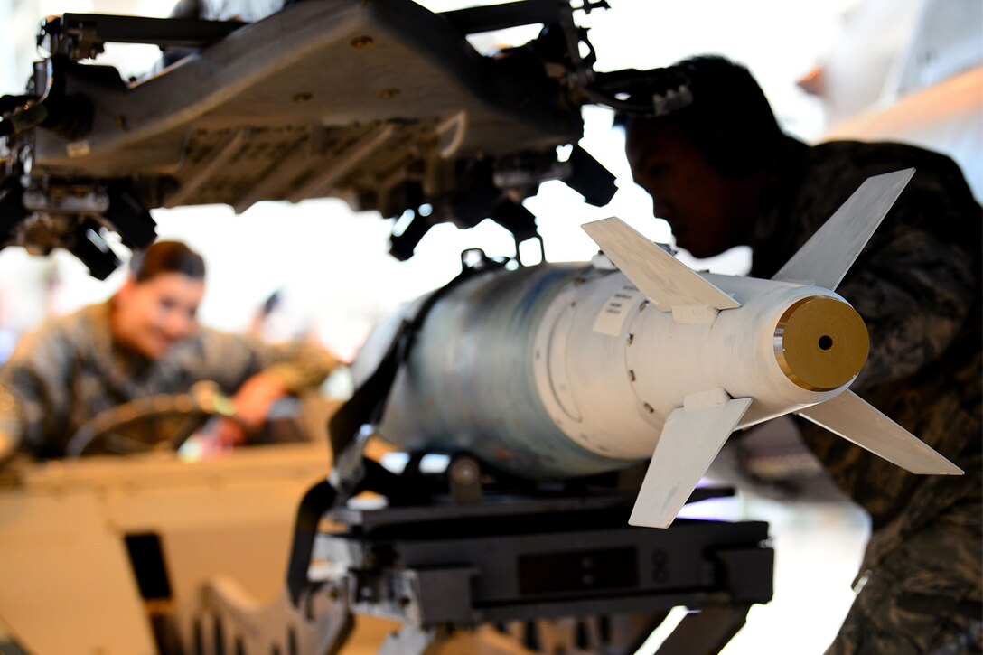 Two airmen load a training weapon.