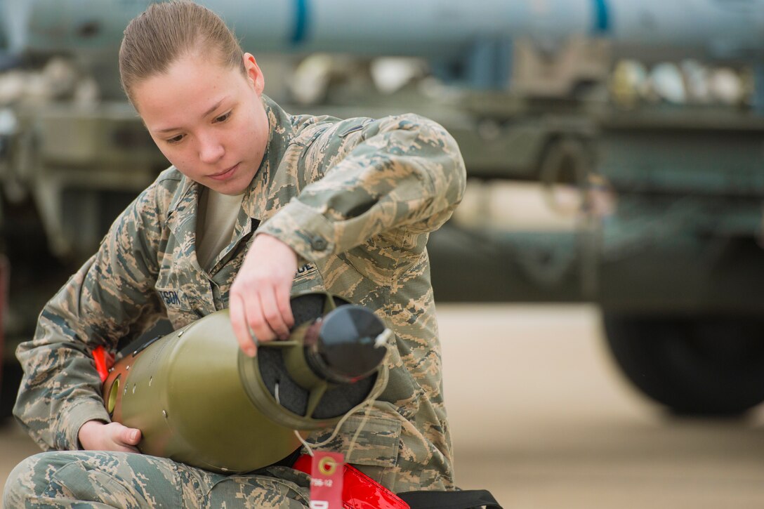 A woman sitting down holds a bomb.