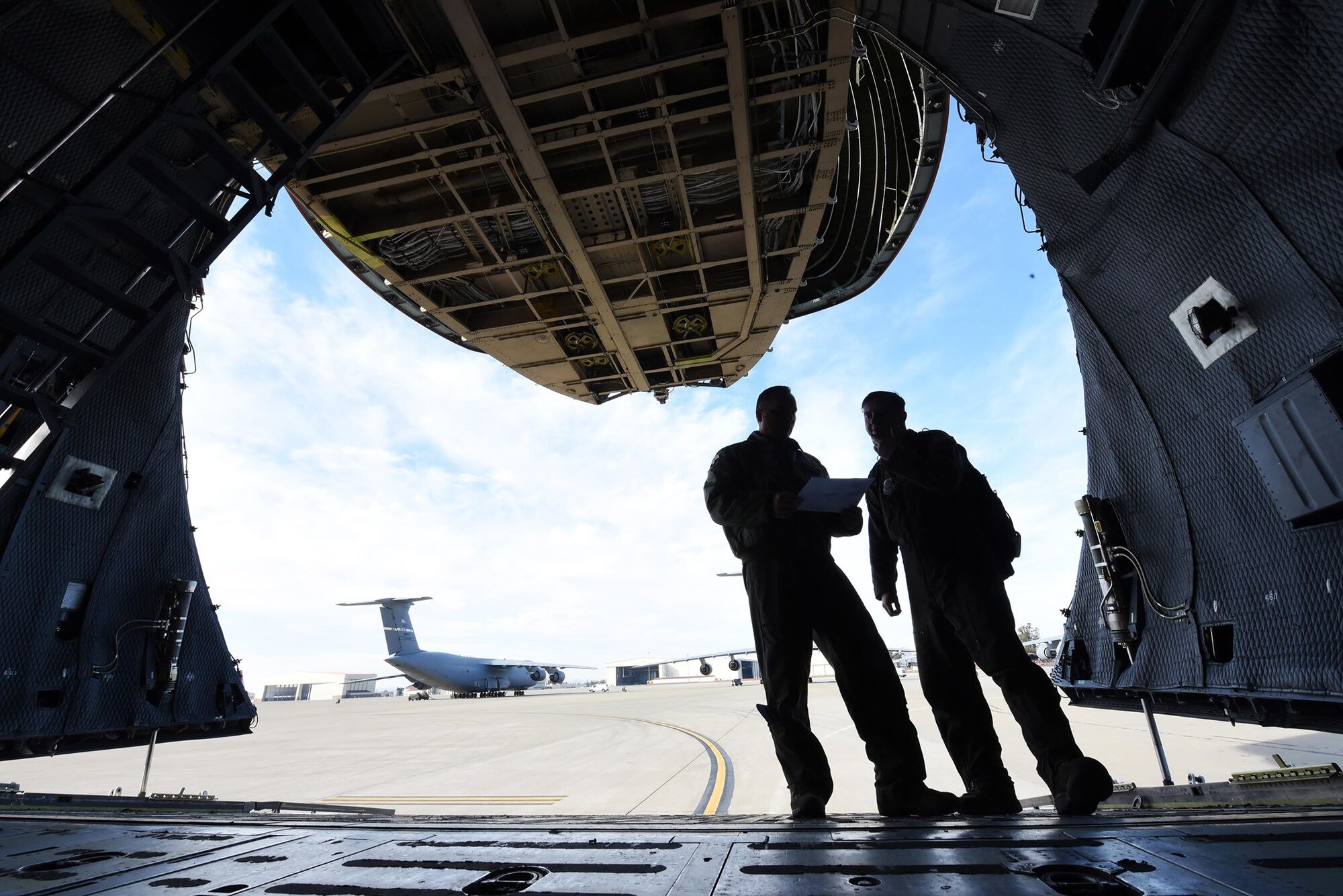 Tech. Sgt. Richard Bline, 312th Airlift Squadron loadmaster, left, and Staff Sgt. Phillip McHenry, 22nd Airlift Squadron loadmaster, right, discuss loading four U.S. Army UH-60 Black Hawks onto the C-5M Super Galaxy they’re inside of January 13 at Travis Air Force Base, Calif. Bline and McHenry were afforded the rare opportunity to train on loading the aircraft as part of training focusing on full-spectrum readiness. (U.S. Air Force photo by Airman 1st Class Christian Conrad)