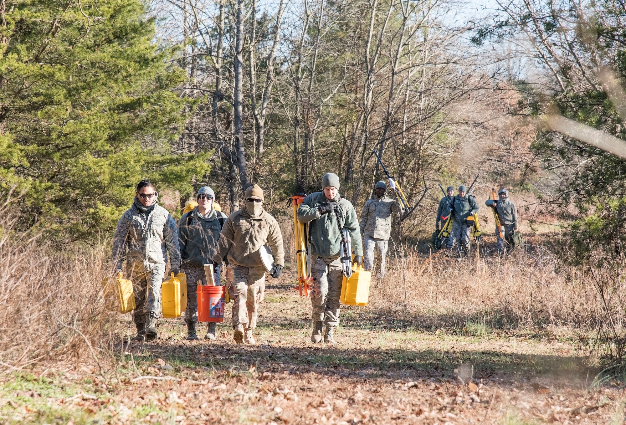 436th Civil Engineer Squadron engineering assistants carry necessary equipment to a debris field during an aircraft mishap survey exercise Dec. 18, 2018, near Killens Pond State Park, Kent County, Del. Survey team members located miscellaneous aircraft and aircrew items of a simulated T-38 Talon aircraft mishap and practiced plotting and documenting each of the items using GPS equipment and a digital camera. (U.S. Air Force photo by Roland Balik)