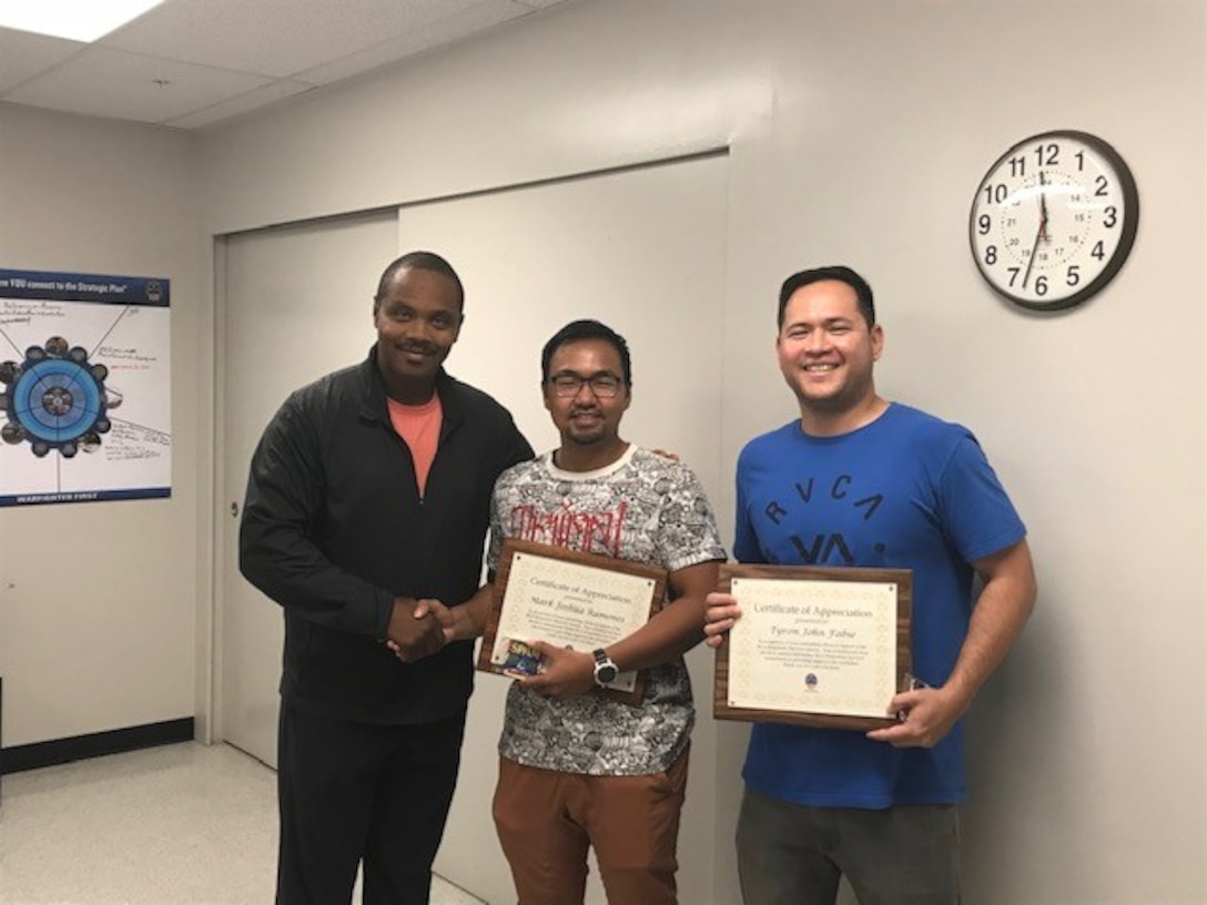 Peter Parker (left), supervisor and disposal services representative, congratulates interns Mark “Josh” Ramones (center) and Tyron Fabie (right) on completing their internships with DLA Disposition Services.