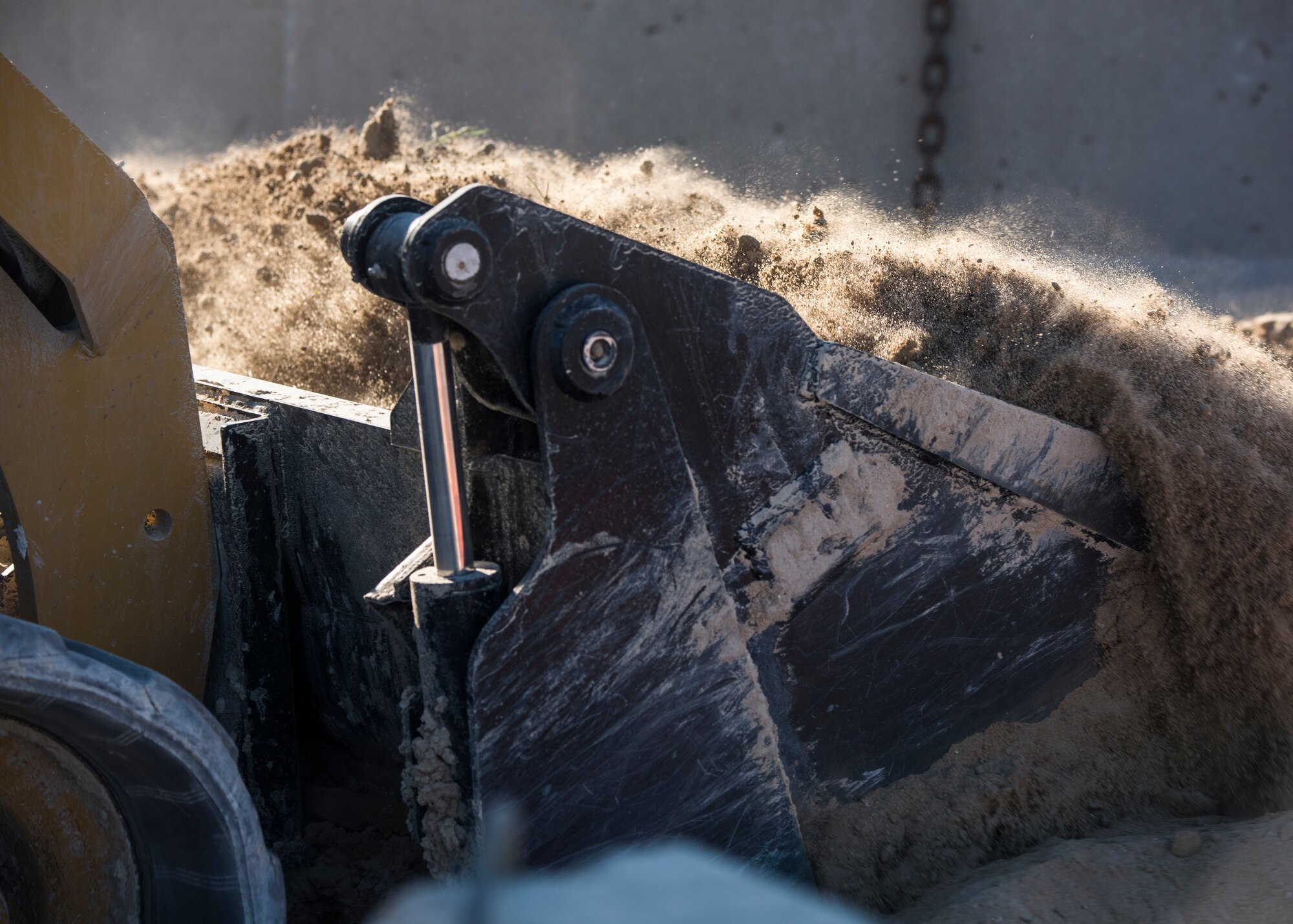 Staff Sgt. Patrick Chuba, 386th Expeditionary Civil Engineer Squadron pavement and equipment journeyman, scoops the sand that was in front of the barriers during the construction of a new road at an undisclosed location in Southwest Asia, Jan. 10, 2019.  Airmen have been working on the road since their arrival to help provide an alternate for large trucks making deliveries