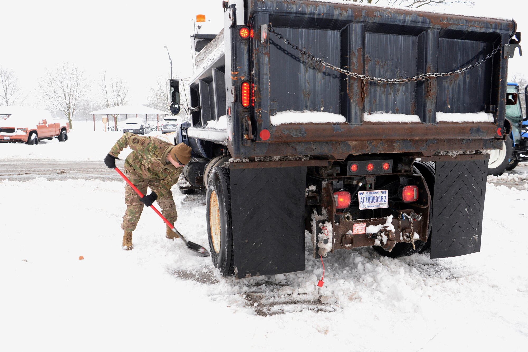 Tech. Sgt. Daniel Brown, 375th Civil Engineer Squadron locksmith NCO in charge, shovels snow away from the tires of a plow truck to give the truck enough traction to continue clearing roads Jan. 12, 2019, at Scott Air Force Base, Illinois. The initial road clearing process takes about three hours but must be continued for as long as the snow is falling to ensure motorists stay safe.