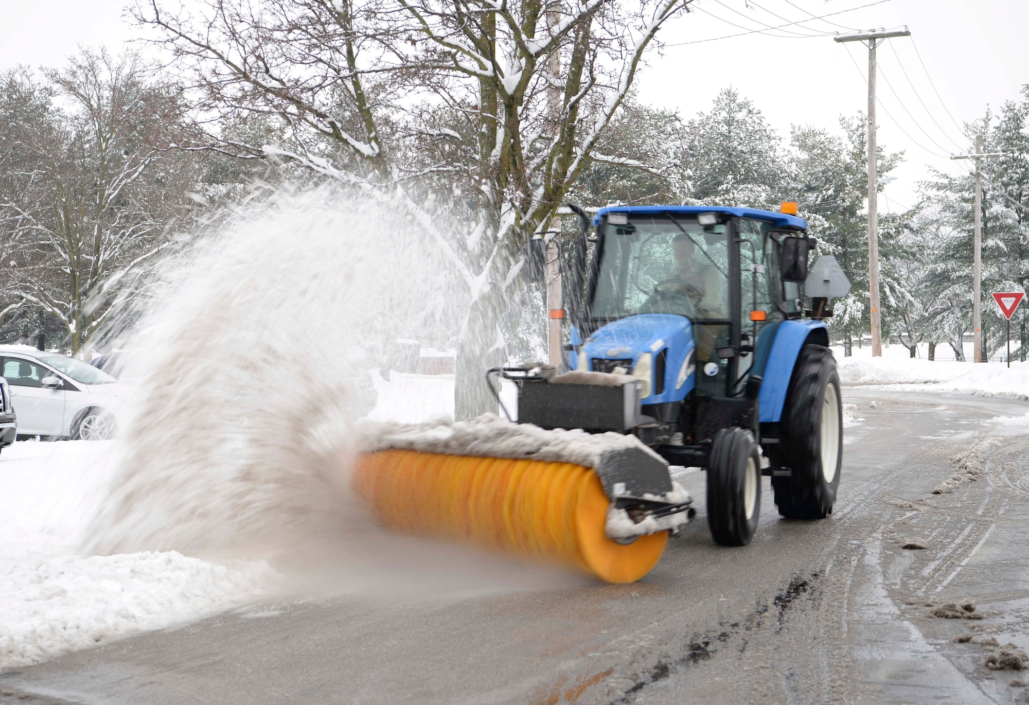 Senior Airman Caleb Lyons, 375th Civil Engineer Squadron water and fuels system maintenance journeyman, uses a tractor and broom to clear snow off the streets Jan. 12, 2019, after heavy snowfall hit Scott Air Force Base, Illinois. Each shift requires about 20 people to aid in the process of clearing the roads.