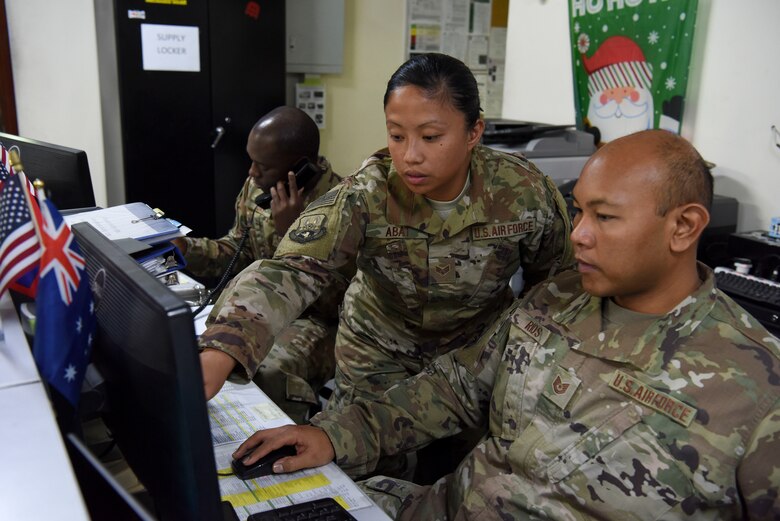 44th Aerial Port Squadron Reservists Staff Sgt. Jordon Day, 380th Expeditionary Logistics Readiness Squadron air transportation craftsman, answers a call while Senior Airman Anna Abat, 380th ELRS passenger service representative and Tech. Sgt. James Rios, 380th ELRS passenger service supervisor, checks the status of a flight, Dec. 24, 2018 at Al Dhafra Air Base, United Arab Emirates.