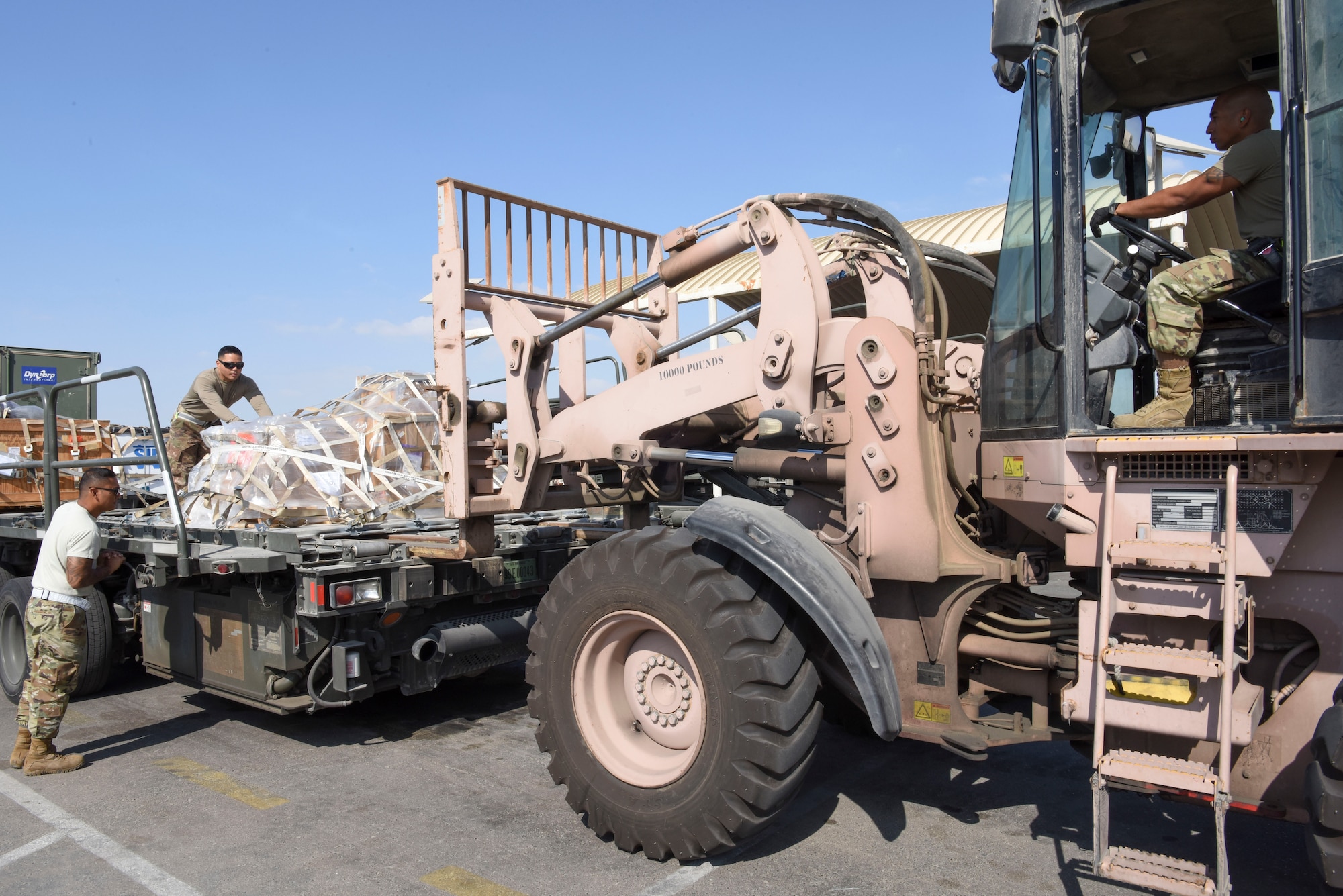 44th Aerial Port Squadron Reservists Staff Sgt. Jonathan Chaco, 380th Expeditionary Logistics Readiness Squadron joint inspector/special handler, and Staff Sgt. Stephen Evaristo, 380th ELRS ramp operations specialist, move cargo onto a forklift drove by Tech. Sgt. Miguel Manibusan, 380th ECES fleet services, Dec. 24, 2018 at Al Dhafra Air Base, United Arab Emirates.