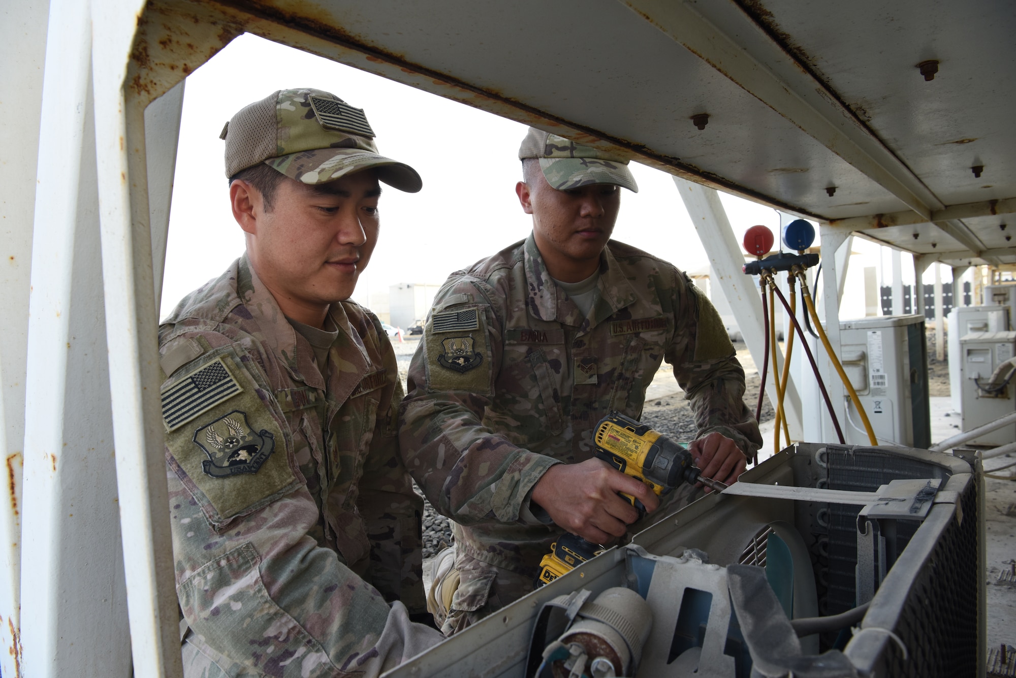 624th Civil Engineer Squadron Reservists Staff Sgt. Roy Shin, 380th Expeditionary Civil Engineer Squadron heating, ventilation, and air conditioning technician, and Senior Airman Elo Badua, 380th ECES HVAC technician, performs maintenance on an air conditioning unit, Jan. 10, 2019 at Al Dhafra Air Base, United Arab Emirates.