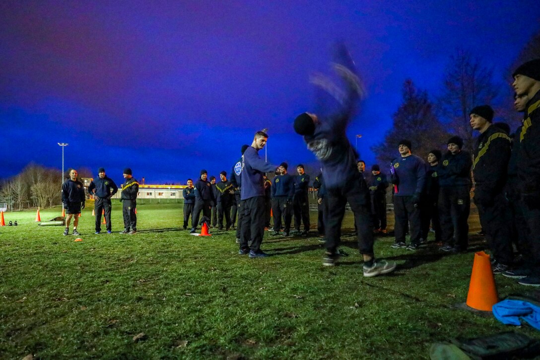 Soldiers watch someone demonstrate a throw.