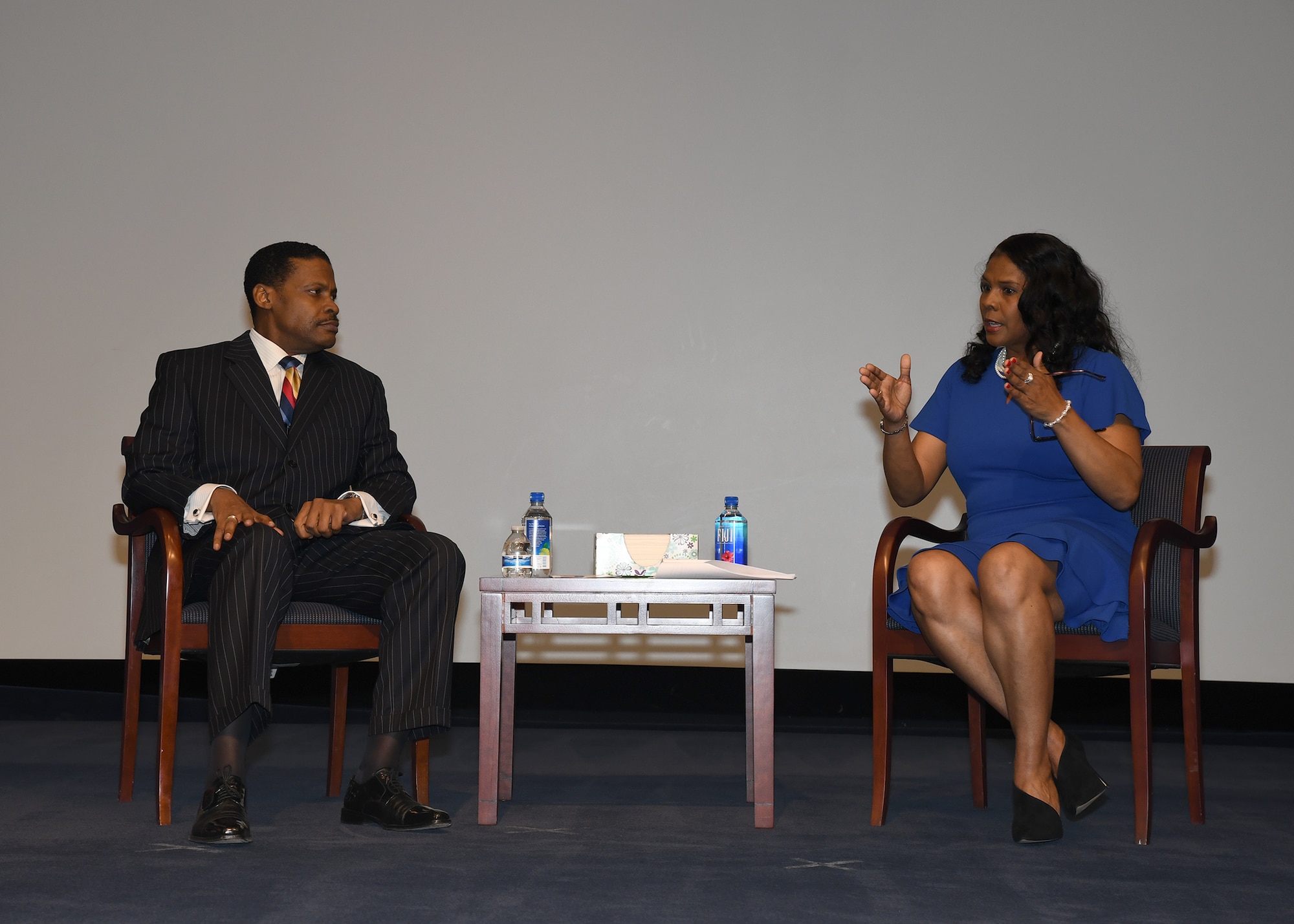 Man, woman seated on stage mid-discussion