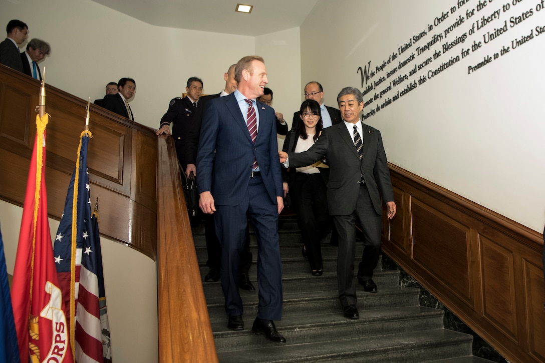 Acting Defense Secretary Patrick M. Shanahan walks down the stairs followed by a group of people.