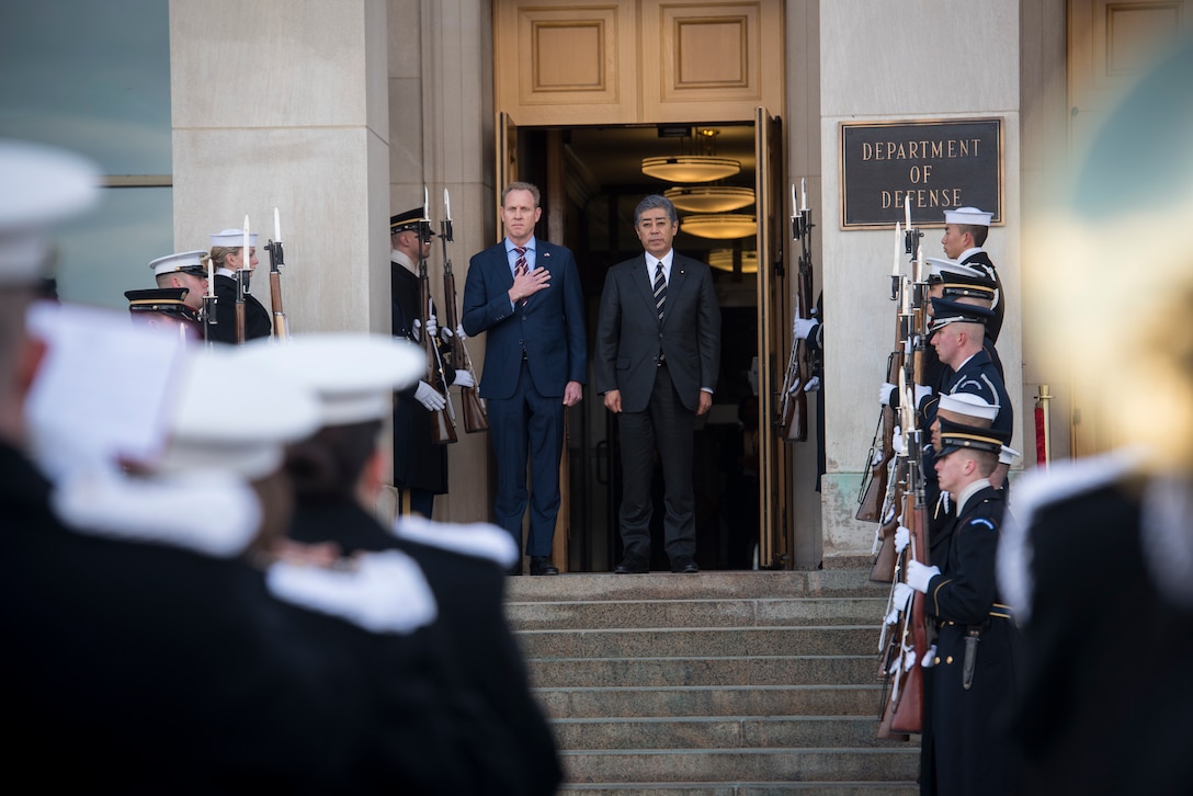 Acting Defense Secretary Patrick M. Shanahan  stands at the top of steps with a Japanese official.