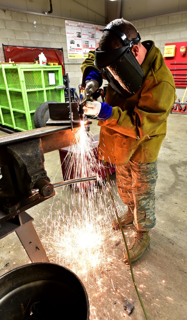 U.S. Air Force Master Sgt. James Childs, 173rd Fighter Wing vehicle maintenance shop, releases a cascade of sparks with a cutting torch during fabrication of a support bracket for a roll-over snow plow, Jan. 14, 2019.