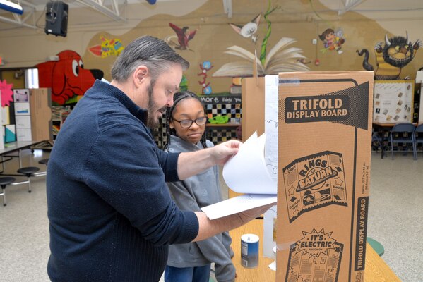 Mark Reed, contract specialist and former science teacher, reviews Marteka Russell’s science project on how salinity affects the buoyancy of an egg. Russell was one of 27 sixth-grade honor students to participate in the science fair Jan. 10, 2019, at the Monte Sano Elementary School in Huntsville, Alabama.