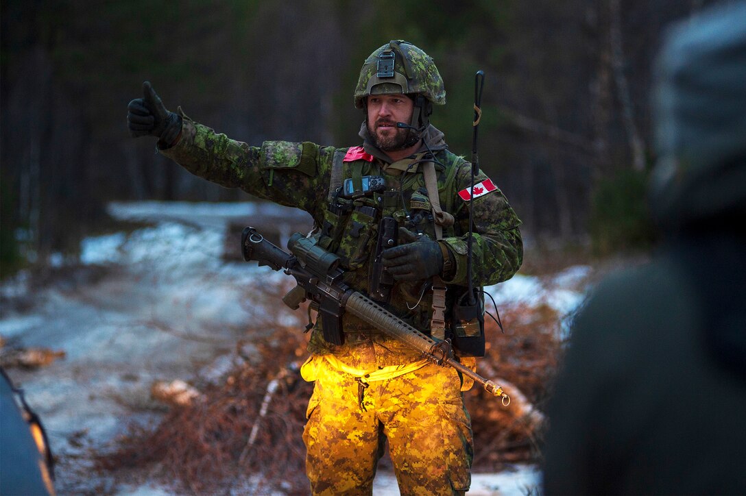 A soldier in camouflage holds a thumbs up.