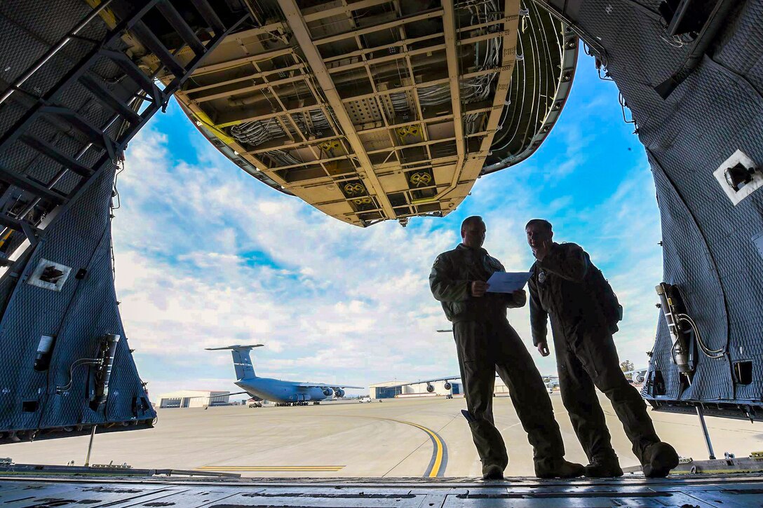 Two airmen discuss loading items into a cargo plane.