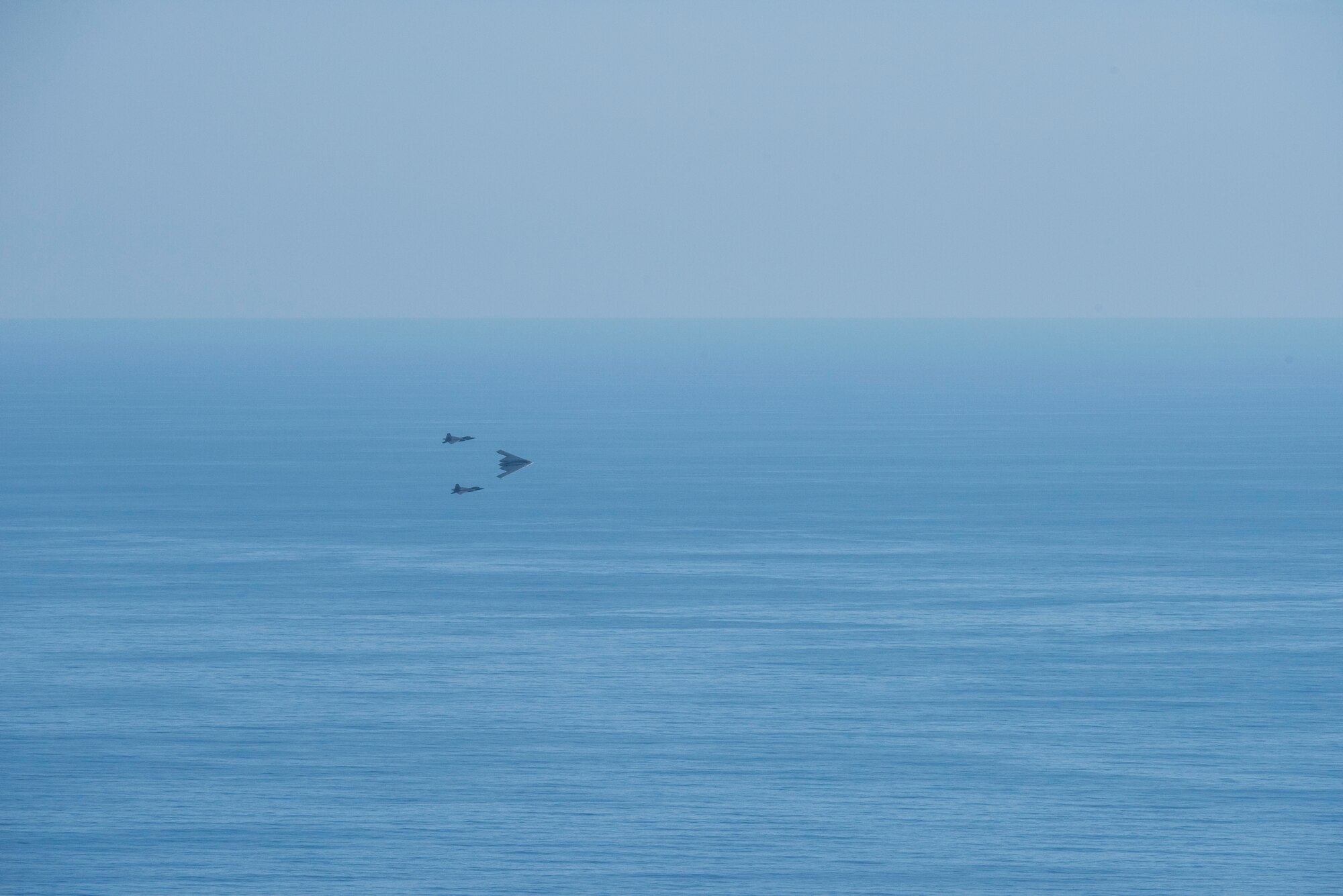 A U.S. Air Force B-2 Spirit bomber deployed from Whiteman Air Force Base, Missouri, and two F-22 Raptors from the 199th Fighter Squadron at Joint Base Pearl Harbor-Hickam, Hawaii, fly in formation near Diamond Head State Monument, Hawaii, after completing interoperability training, Jan. 15, 2019.