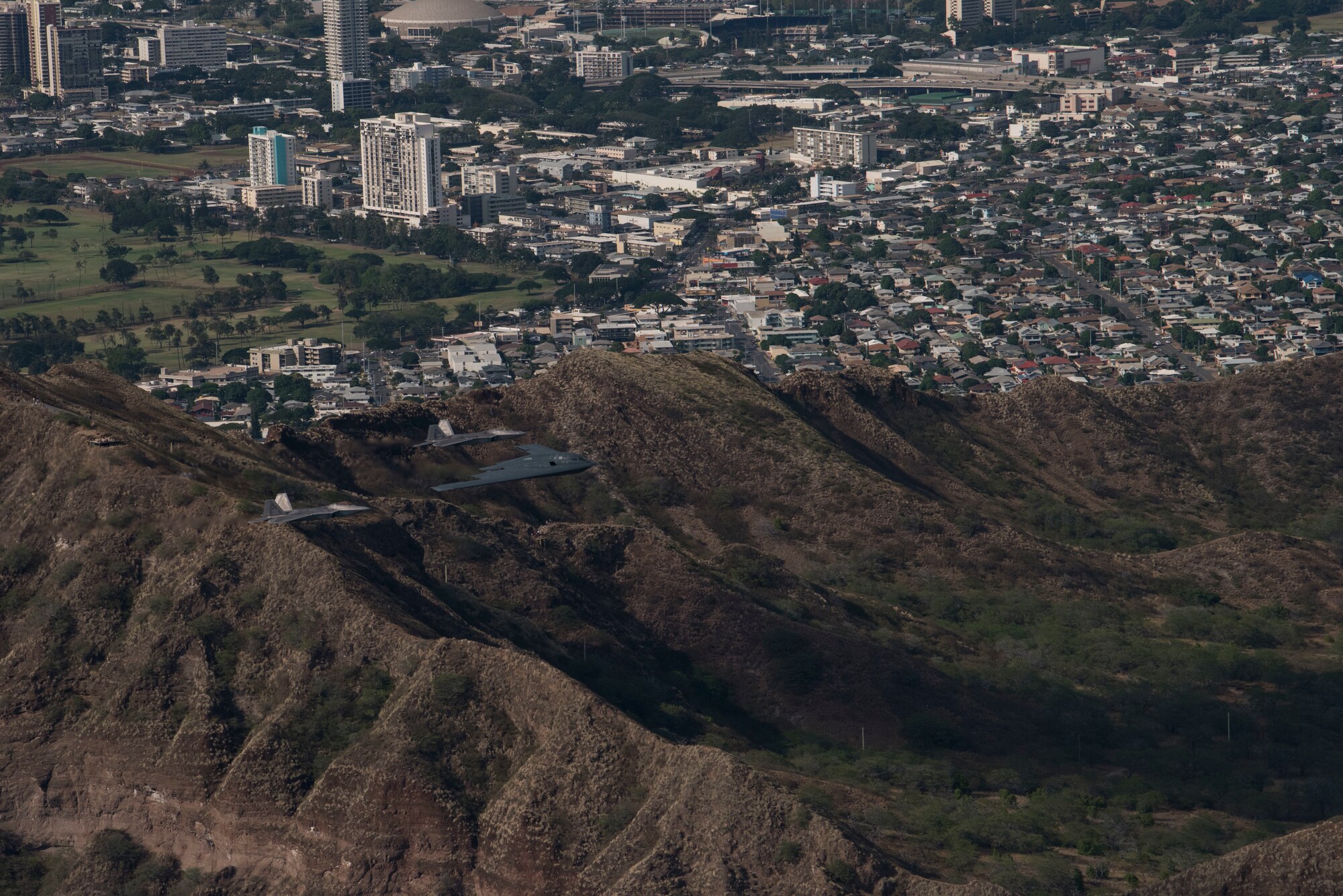 A U.S. Air Force B-2 Spirit bomber deployed from Whiteman Air Force Base, Missouri, and two F-22 Raptors from the 199th Fighter Squadron at Joint Base Pearl Harbor-Hickam, Hawaii, fly in formation near Diamond Head State Monument, Hawaii, Jan. 15, 2019.