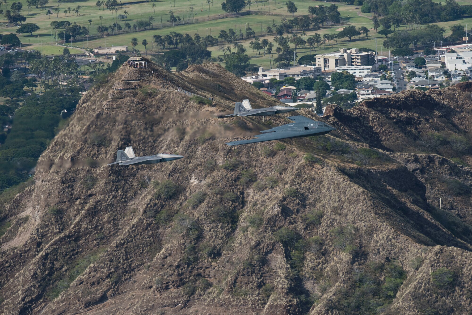 A U.S. Air Force B-2 Spirit bomber deployed from Whiteman Air Force Base, Missouri, and two F-22 Raptors from the 199th Fighter Squadron at Joint Base Pearl Harbor-Hickam, Hawaii, fly in formation near Diamond Head State Monument, Hawaii, during an interoperability training mission Jan. 15, 2019.