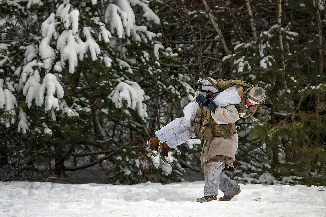 A soldier carries another soldier during training in the snow.