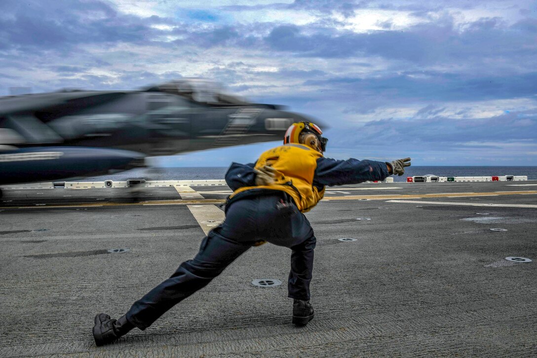 A sailor signals to a plane to go.