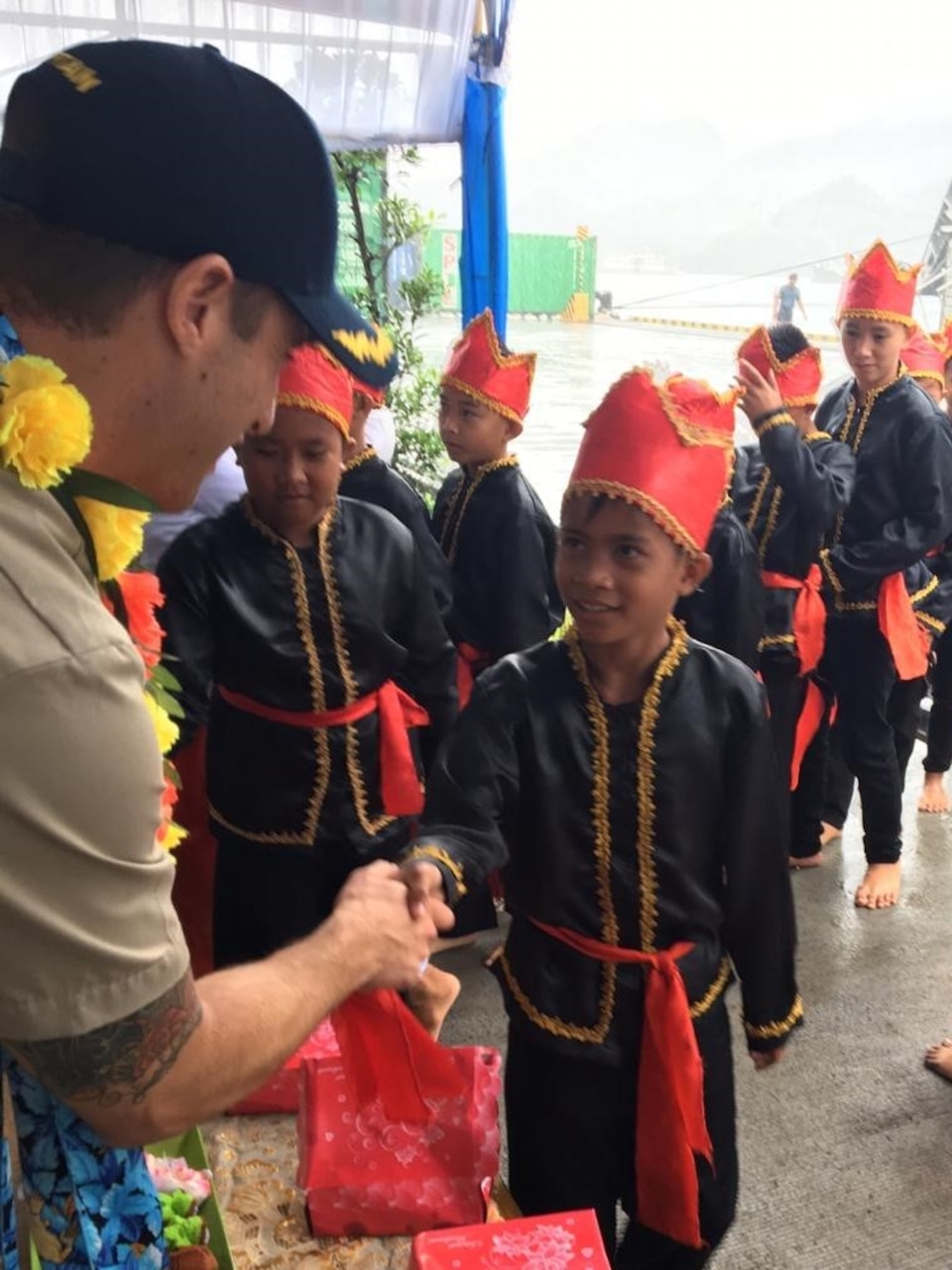 Civilian mariner Capt. Adam Streeper, ship’s master of the expeditionary fast transport ship USNS Brunswick (T-EPF 6), shakes hands with local elementary school students after the ship arrived in Bitung, Indonesia, for a scheduled port visit. Brunswick is one of three expeditionary fast transport ships in the U.S. 7th Fleet area of responsibility with a mission of providing rapid intra-theater transport of troops and military equipment.