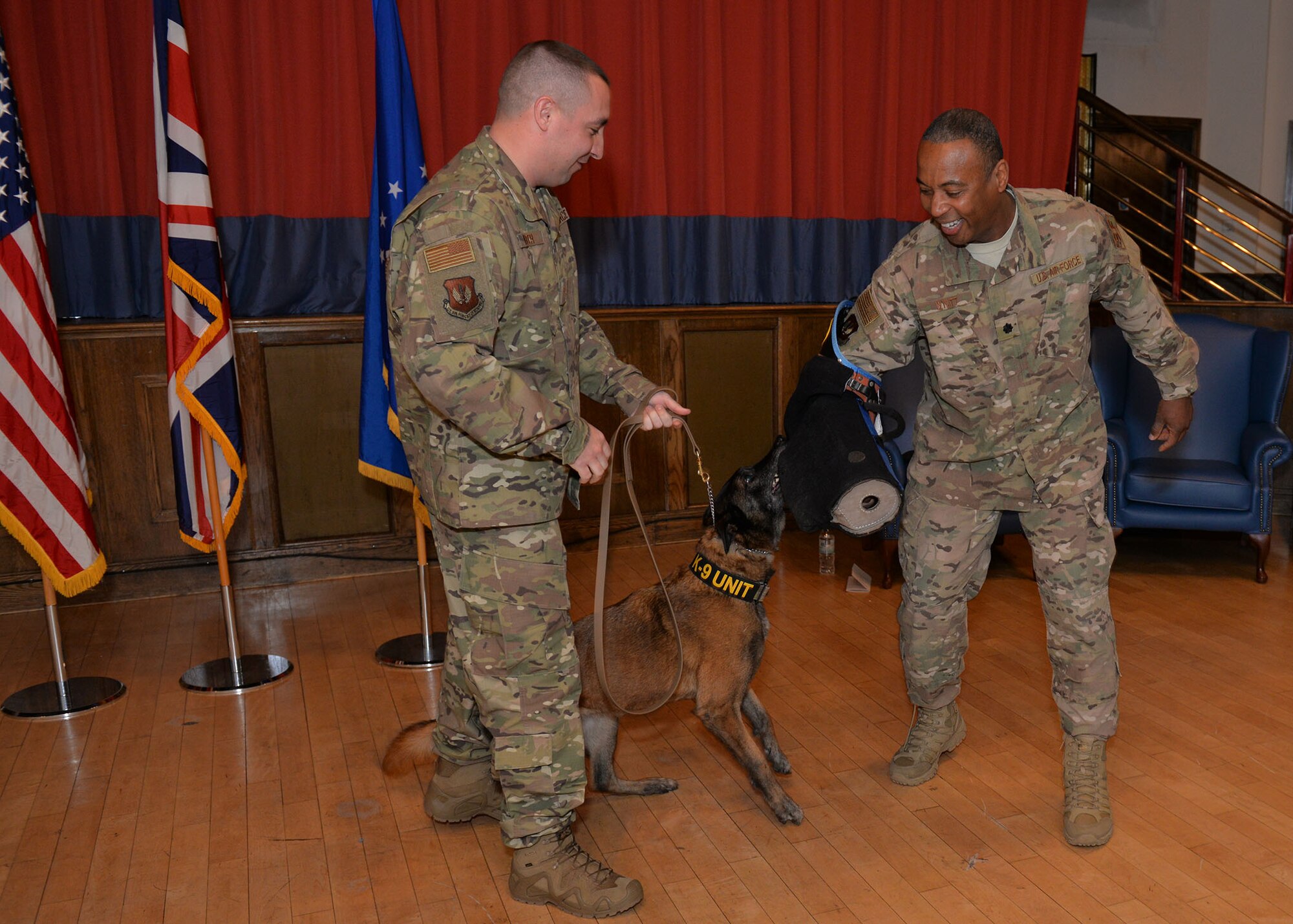U.S. Air Force Lt. Col. Lawrence Wyatt, right, 100th Security Forces Squadron commander, shows the bite sleeve to Military Working Dog Vvonya, held by Tech. Sgt. Kelly Webster, 100th SFS MWD kennel master, for her last bite during her retirement ceremony at RAF Mildenhall, England, Jan. 18, 2019. Webster and his family have adopted Vvonya as she retires after nine years military service. (U.S. Air Force photo by Karen Abeyasekere)