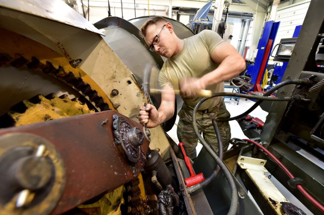 Tech. Sgt. Jacob Graham, a 173rd Fighter Wing vehicle operations mechanic, removes a cotter pin from a damaged plow roll-over assembly, Jan. 8, 2019 at Kingsley Field in Klamath Falls, Ore. The parts for this older plow are growing harder to find, and the mechanics will have to fabricate one part on-site in order to return this snow plow to service. (U.S. Air National Guard photo by Tech. Sgt. Jefferson Thompson)