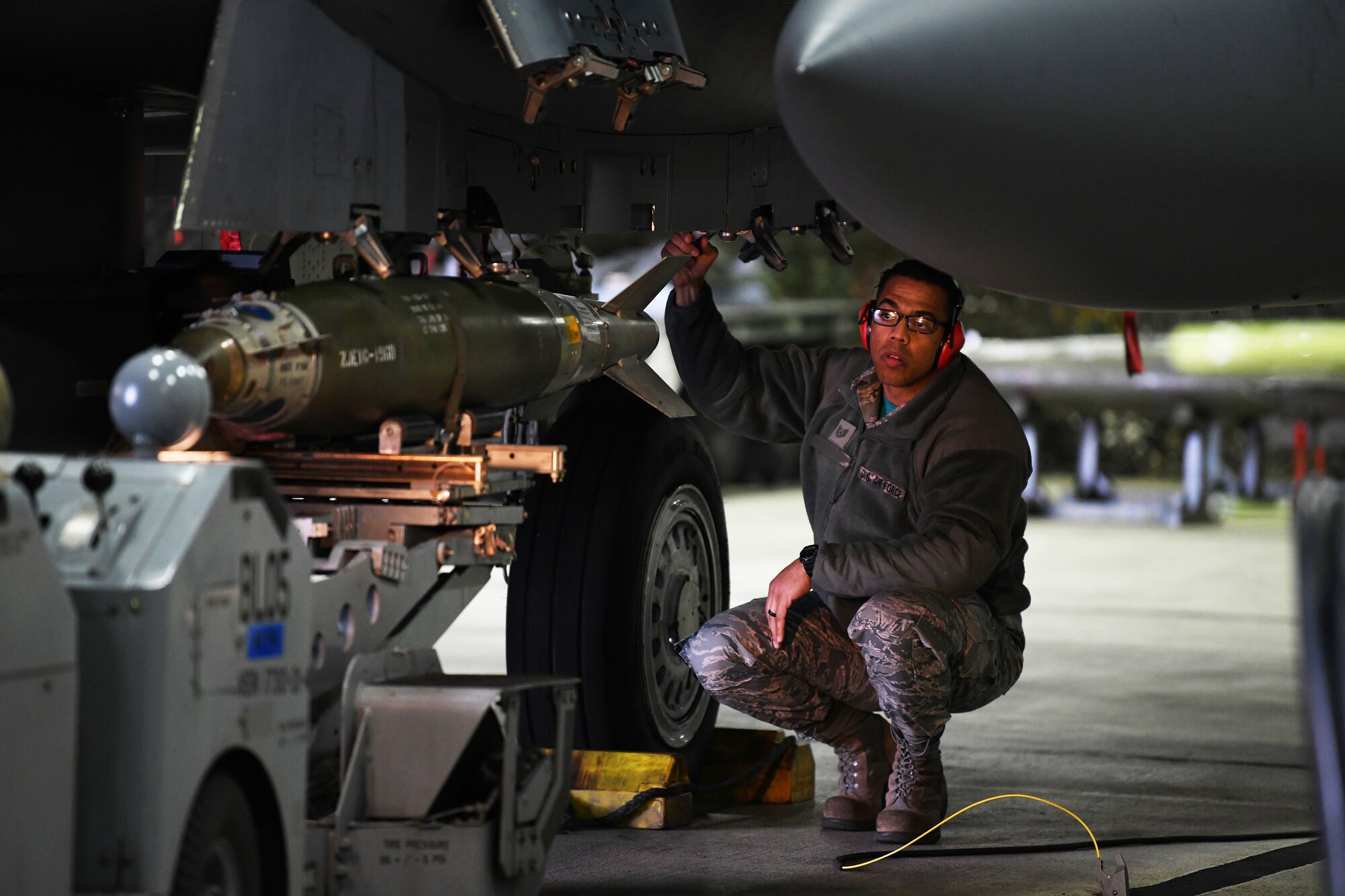 A loading standardization crew member observes the loading of an inert MK-82 ordinance on an F-15E Strike Eagle during a loading competition at Royal Air Force Lakenheath, England, Jan. 18, 2019. The load crew team were judged on their ability to load both an inert MK-82 and a GBU-38 on the aircrafts. (U.S. Air Force photo by Airman 1st Class Shanice Williams-Jones)