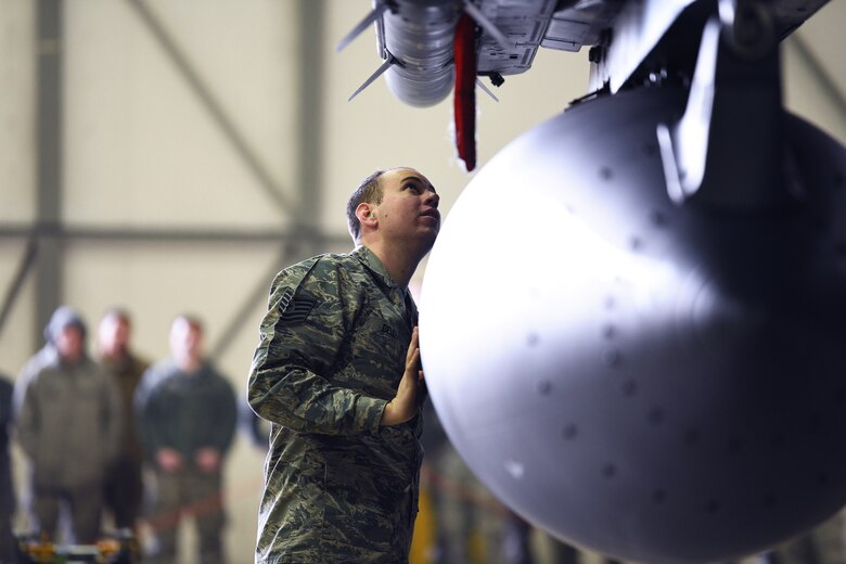 A loading standardization crew member reviews the work of a load crew team at a weapons loading competition at Royal Air Force Lakenheath, England, Jan. 18, 2019. The 3-person teams representing the 492nd, 493rd and 494th Aircraft Maintenance Units, raced against the clock to see who could complete their tasks safely and with accuracy. (U.S. Air Force photo by Airman 1st Class Shanice Williams-Jones)