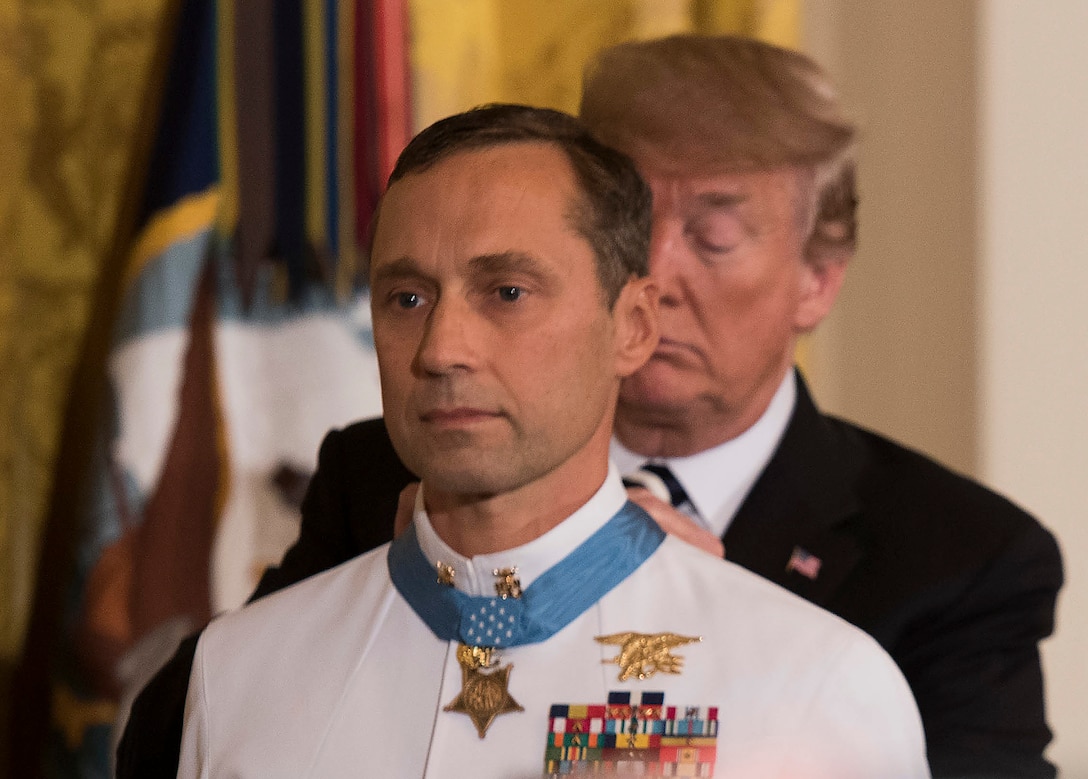 President Trump places the Medal of Honor around a recipient's neck.