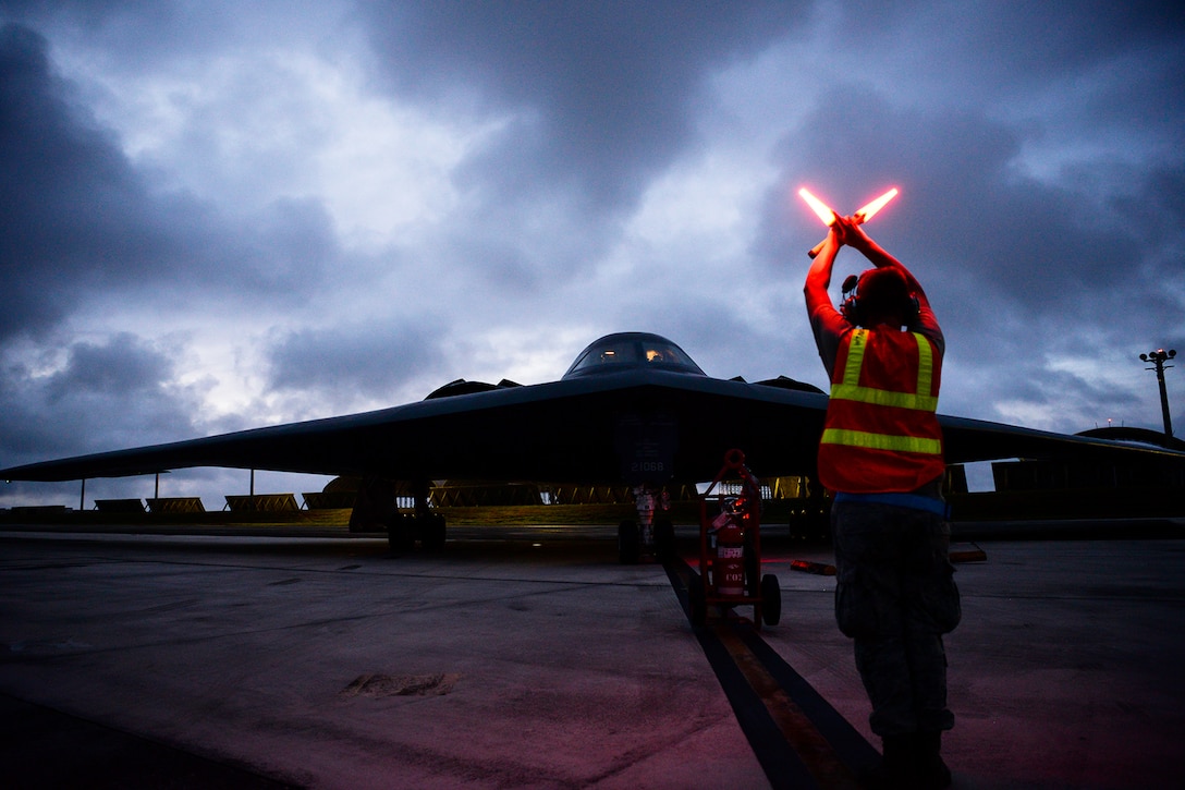 An airman  signals to a B-2 Spirit bomber